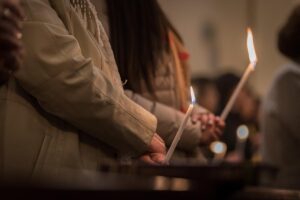 The torsos of two people holding lit candles